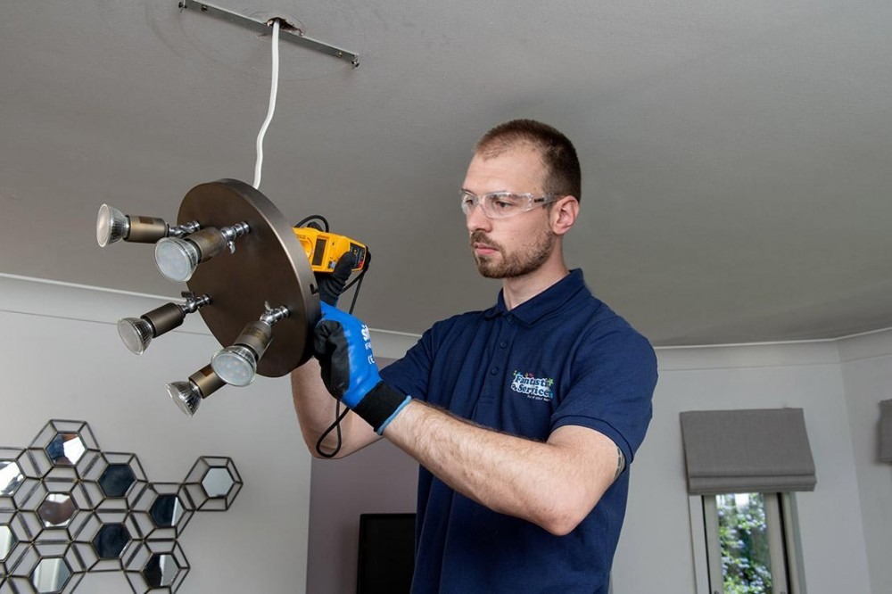 An electrician repairs lighting in a house.